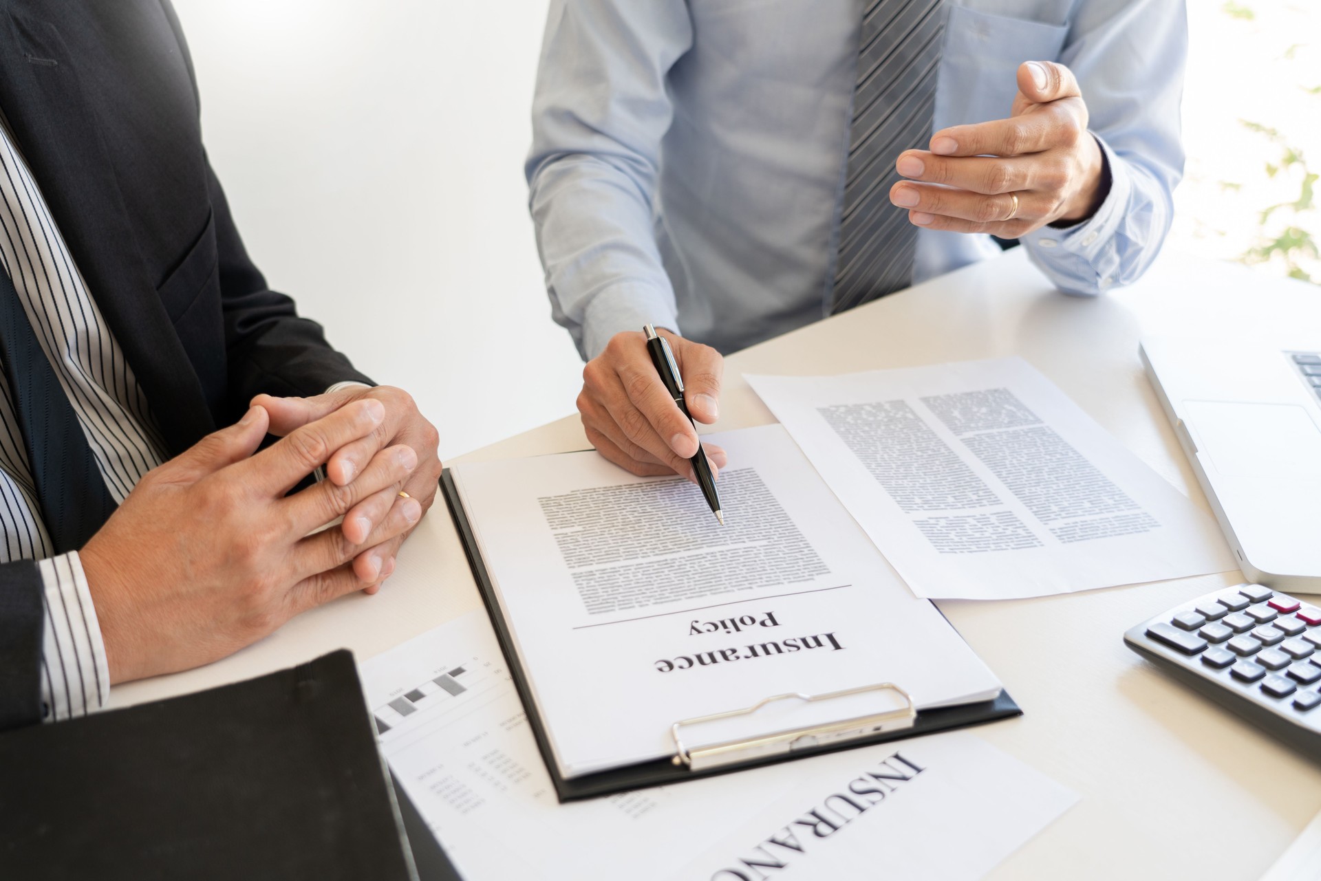 Midsection Of Insurance Agent Discussing With Client On Table