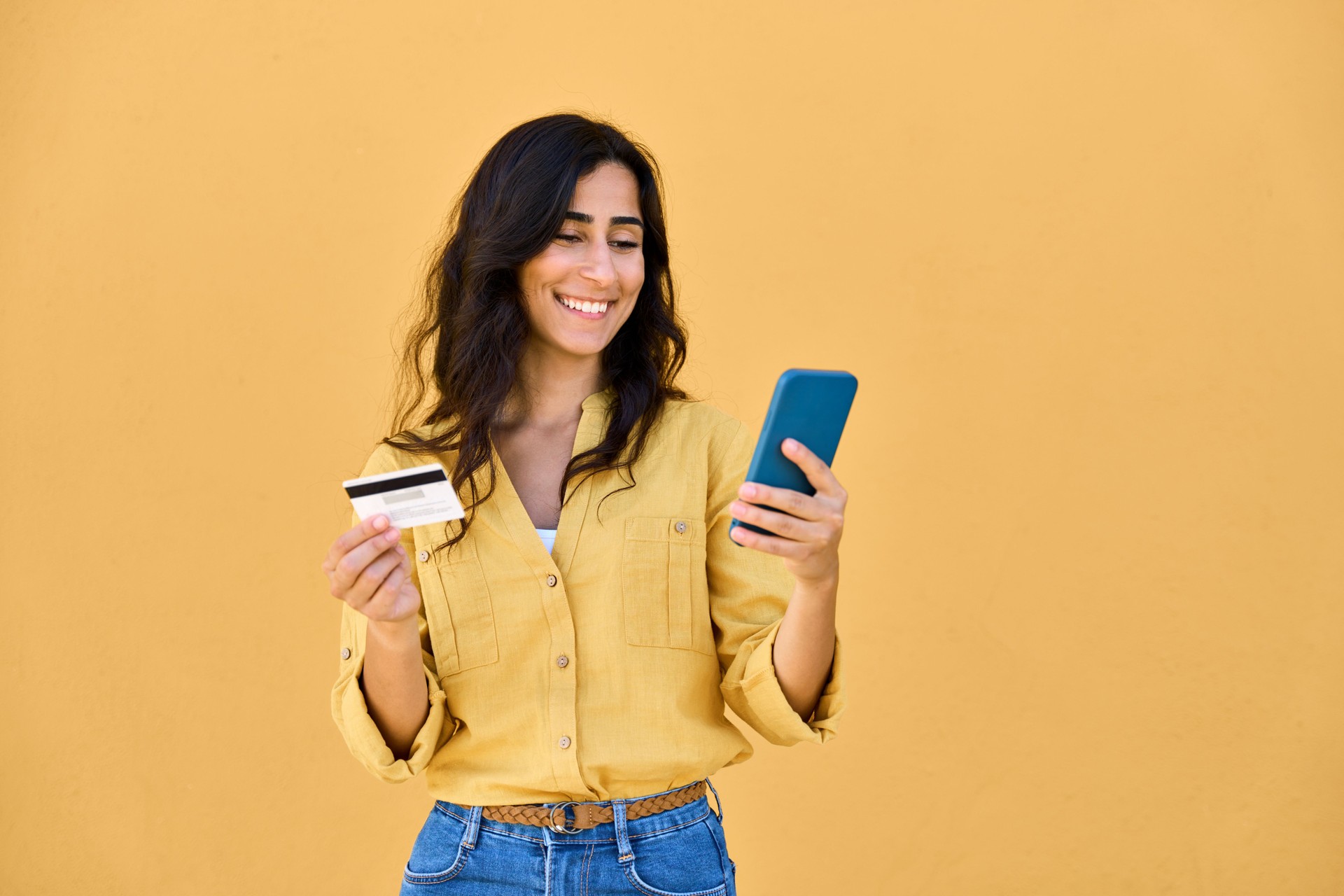 Joven empresaria de Oriente Medio con teléfono móvil móvil, tarjeta bancaria de débito y crédito aislada. Indios, compradora árabe, mujer de negocios que usa el teléfono inteligente para comprar, comprar, comercio electrónico en línea